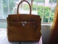 Bolsa em couro, amarela, com cadeado.